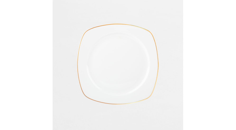 Zestaw obiadowy z białej porcelany o geometrycznym kształcie. Ma pozłacane brzegi.